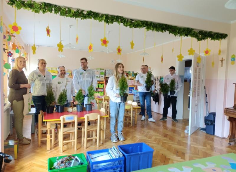 Pani Dyrektor i przedstawiciele firmy EMKA S.A. trzymający drzewka - tuje w donicach.