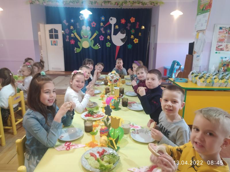Dzieci jedzą  śniadanie przy udekorowanych stolach