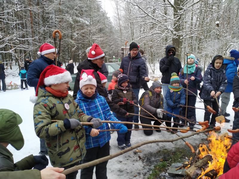 Leśna śnieżna droga. Uczniowie szkoły z rodzicami przy ognisku pieką kiełbaski.