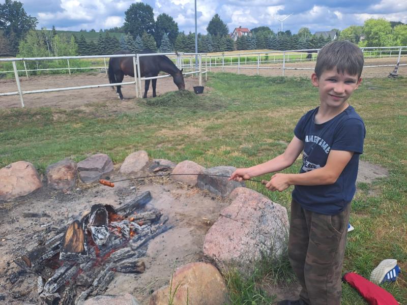 Uczeń klasy 2b smaży kiełbaskę w ognisku przy stadninie koni.