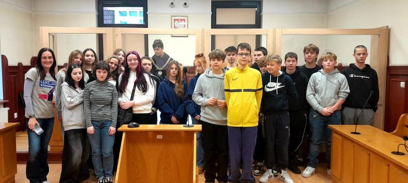 Zdjęcie grupowe uczni&oacute;w klasy si&oacute;dmej na sali sądowej