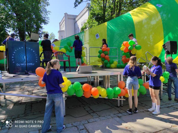 Wolontariusze dekorują balonami scenę wykorzystana podczas Obchodów Dnia Godności Osób z Niepełnosprawnością Intelektualną.