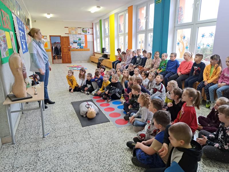 Uczniowie klas pierwszych na szkolnym holu odbywają szkolenie z pierwszej pomocy medycznej