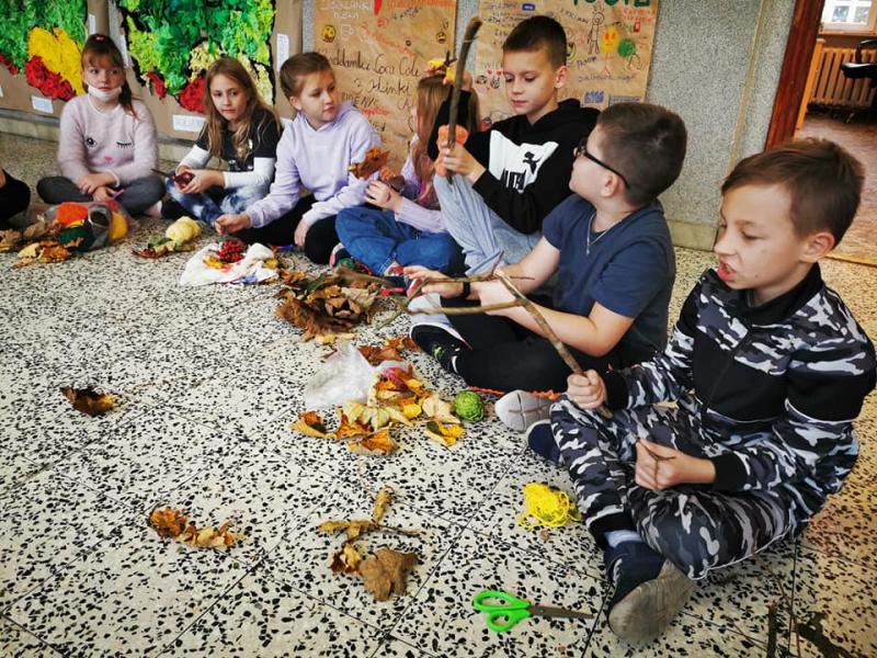 Uczniowie klas 3 siedzą w kole, tworzą dekoracje jesienne