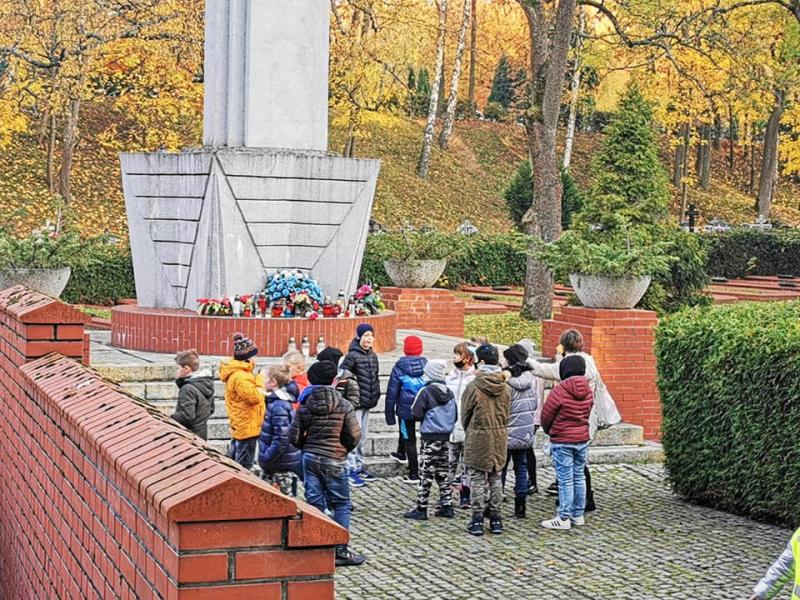 Uczniowie klas 1-3 na cmentarzu porządkują groby i zapalają znicze.