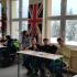 Uczniowie różnych szkół w ławkach sali językowej podczas międzyszkolnego quizu wiedzy o krajach anglojęzycznych.