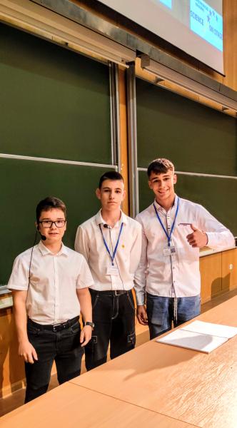 Uczniowie :Bartek, Jurek i Marcin stoją w gotowości do przedstawiania projektu konkursowego. Stoją w sali wykładowej na uniwersytecie Adama Mickiewicza w Poznaniu Wydział fizyki.