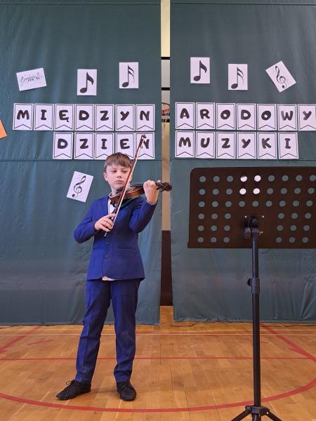 Uczeń klasy trzeciej gra na skrzypcach na szkolnym koncercie