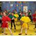 Zdjęcie przedstawia dzieci w kolorowych strojach śpiewające Optymistyczny Hymn