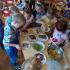 Na zdjęciu widzimy grupy dzieci przy stolikach, które przygotowująszaszłyki owocowe (winogrona, brzoskiwie)