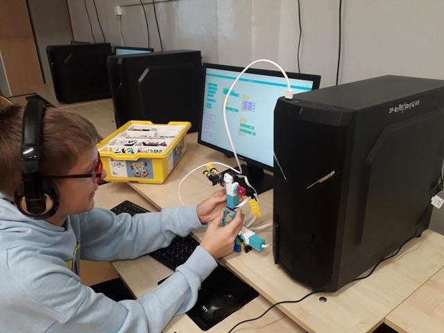 Uczniowie w sali komputerowej budują i programują robota