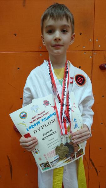 Szymon Michułka z trzema medalami oraz dyplomami.