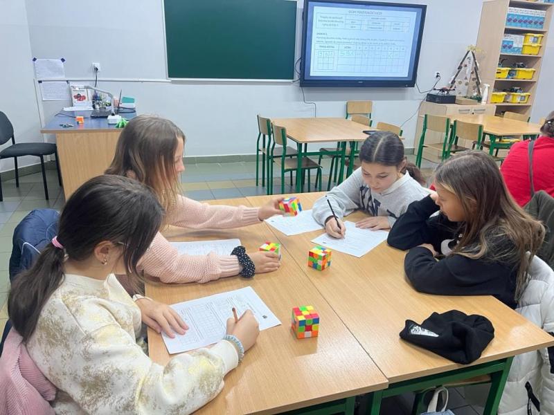 Uczniowie przy stoliczkach podczas zajęć z użyciem kostki Rubika na matematyce w SP5