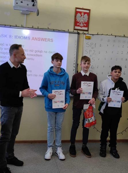 Zdjęcie laureatów quizu z dyrektorem i nauczycielem przez tablicą