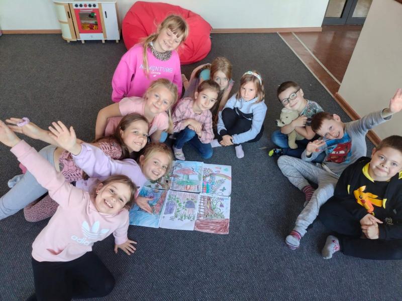 Uczniowie świetlicy pozuja do zdjecia przy kartkach z pracami plastycznymi