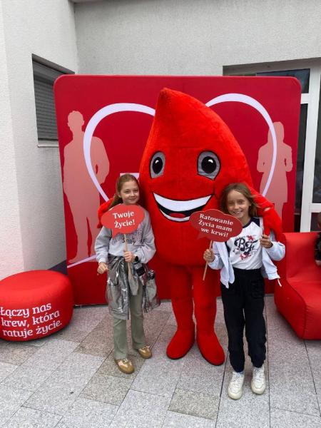 Zdjęcie uczniów z maskotką przed Centrum Krwiodawstwa i Krwiolecznictwa