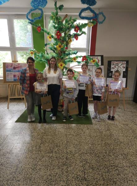 Na zdjęciu laureaci konkursu My Picture Dictionary z klas I-III z nauczycielkami języka angielskiego w edukacji wczesnoszkolnej. W tle instalacja drzewa.