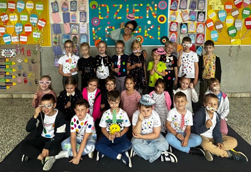 Zdjęcie grupowe klasy edukacji wczesnoszkolnej z wychowawczynią. Uczniowie ubrani w stroje w kropki.
