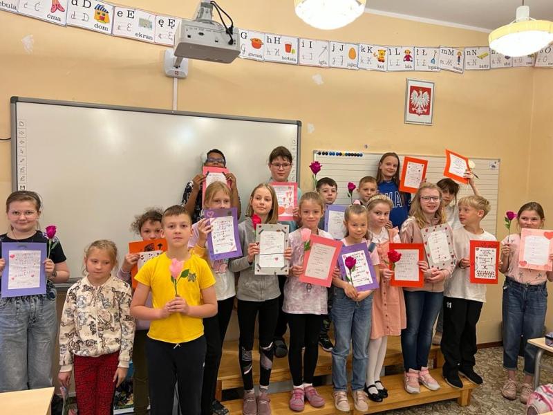 Uczniowie klasy trzeciej przed tablicą z laurkami dla mam