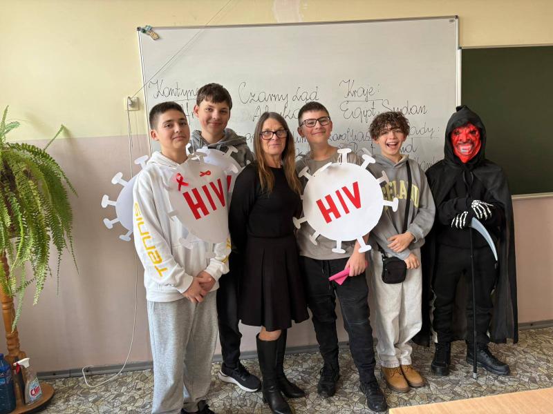 Zdjęcie grupowe uczniów z banerami profilaktycznymi HIV