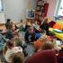 Uczniowie klasy 1a w Miejskiej Bibliotece Publicznej Filia nr. 7 w Słupsku. Uczniowie siedzą na podłodze słuchając opowieści bibliotekarki.